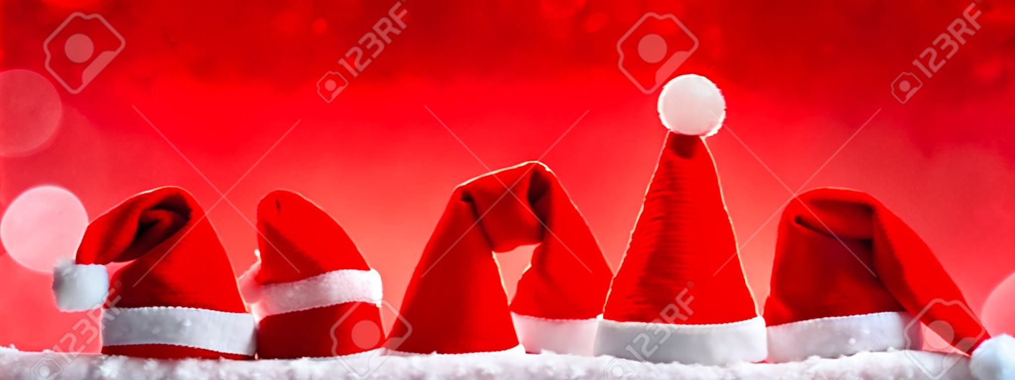 Siedem czerwonym kapelusze Santa samodzielnie na czerwonym background.Christmas czerwonym tle z Christmas hats.Red Christmas kapelusze.