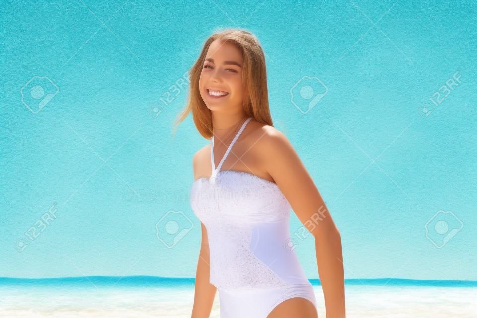 Bella ragazza, felice sulla spiaggia in un vestito di nuoto