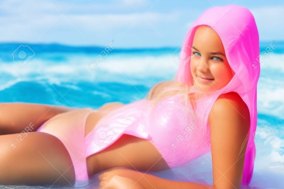 Adolescente, niña en rosa traje de baño en la playa