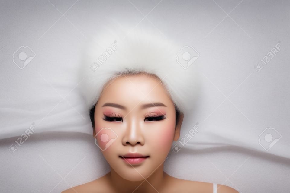 Close up beautiful young Asian girl lying on white with scatter hair