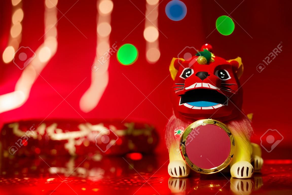 Chinese new year festival decorations, miniature dancing lion on red glitter background.