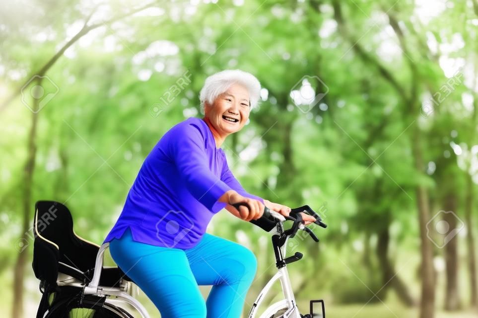 Aktif yaşlı Asyalı kadın Bisiklete binme, kıdemli yetişkin etkinliği, sabah açık bisiklet sürme.