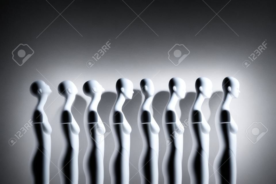 White Woman Torso Figurines Standing in The Line All Looking to Same Direction except of One, shoot in Dark Mood with Spotlight