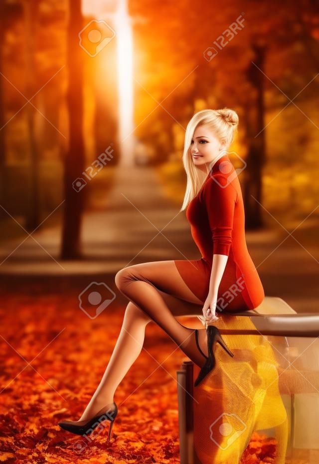Piękna blond kobieta z idealnymi nogami w rajstopach pozowanie odkryty na jesiennej ulicy w świetle zachodzącego słońca.