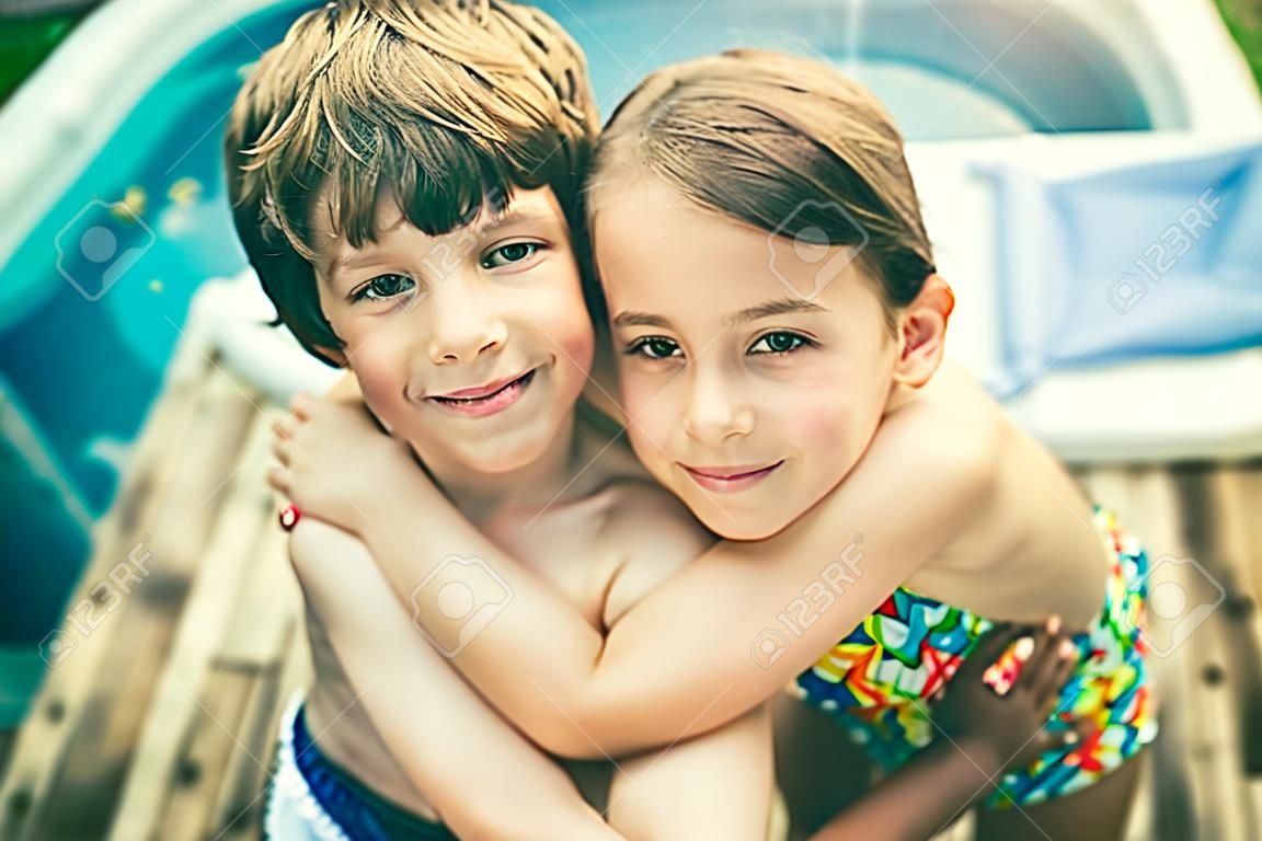 Fratello e sorella che abbracciano in costume da bagno davanti a una vasca idromassaggio