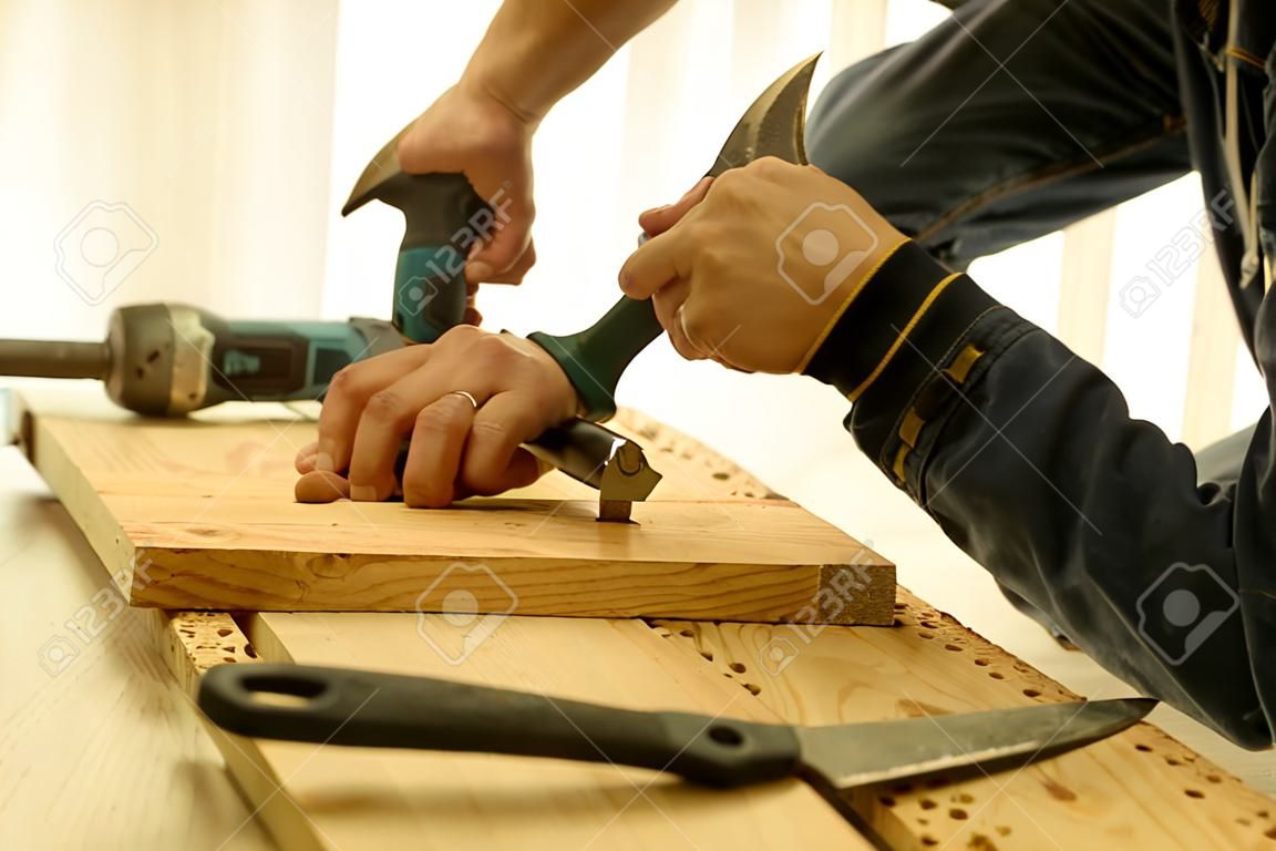 Sluiten van het hameren van een spijker in houten plank