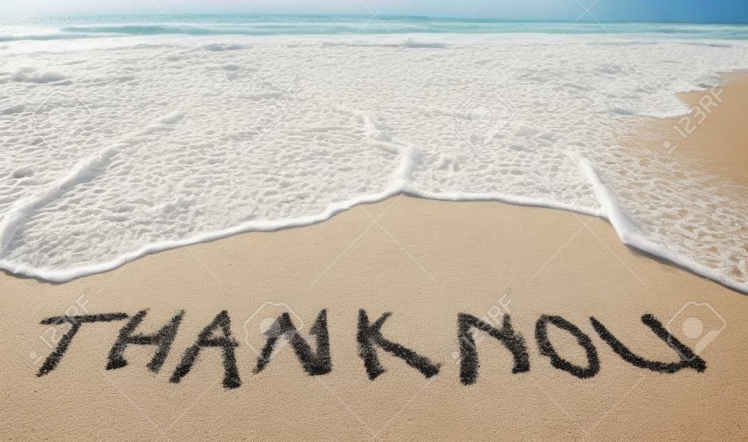 thank you words written on the sand of the beach