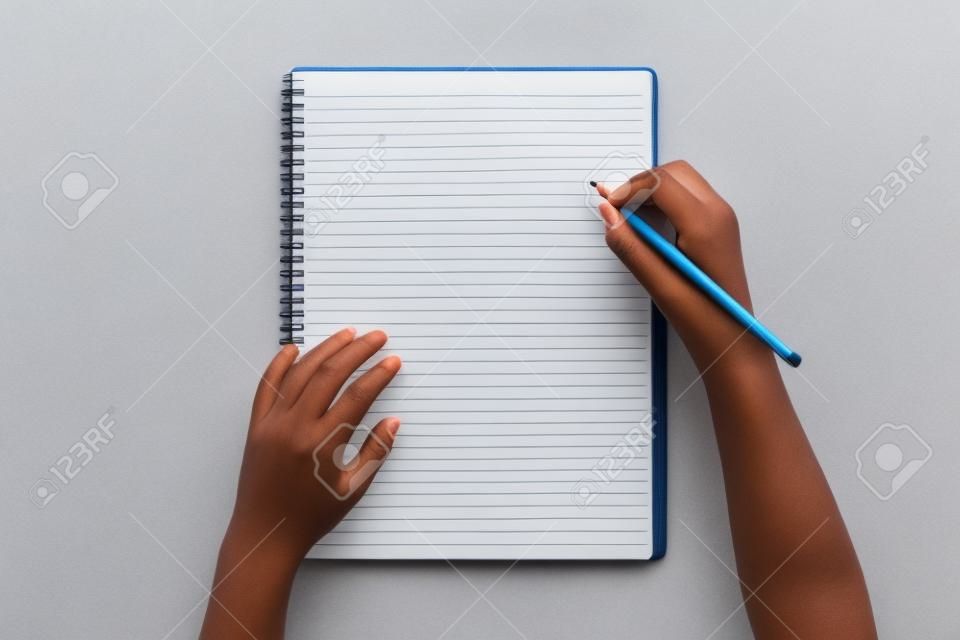Mãos em uma mesa com um lápis e um caderno em branco no fundo branco. Flat leigos com espaço de cópia para blogueiros