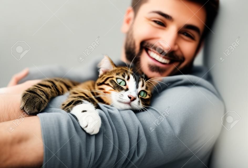 Cute smiling happy cat lying on the mans shoulder