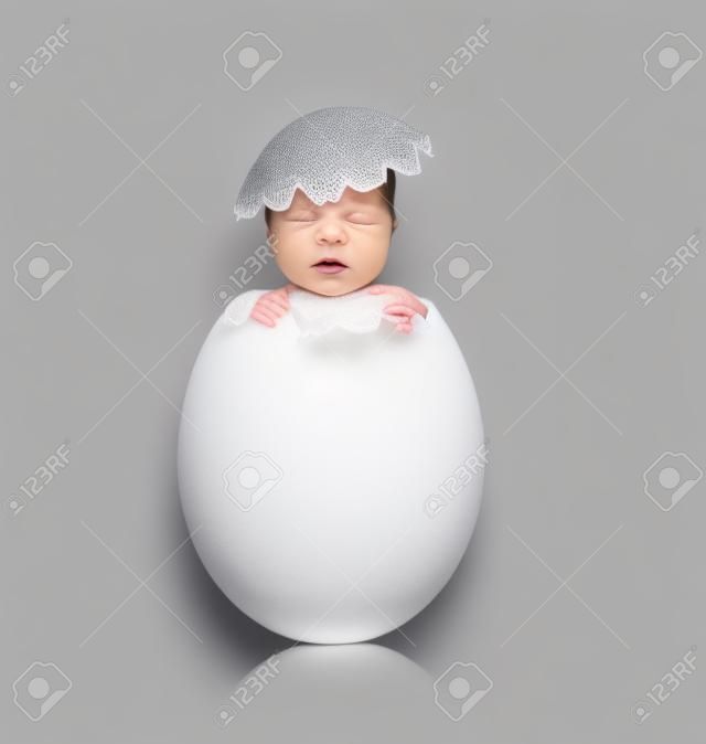 회색 배경에 신생아 아기와 함께 한 흰색 달걀, 부화