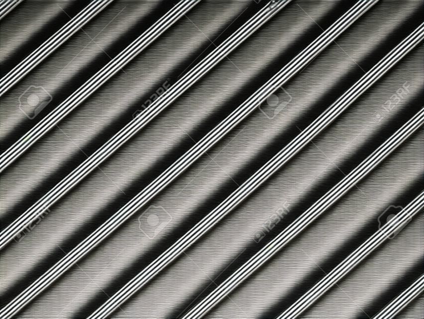 Close-up of aluminum cover grille with pattern of diagonal lines in shadow and light, black and white