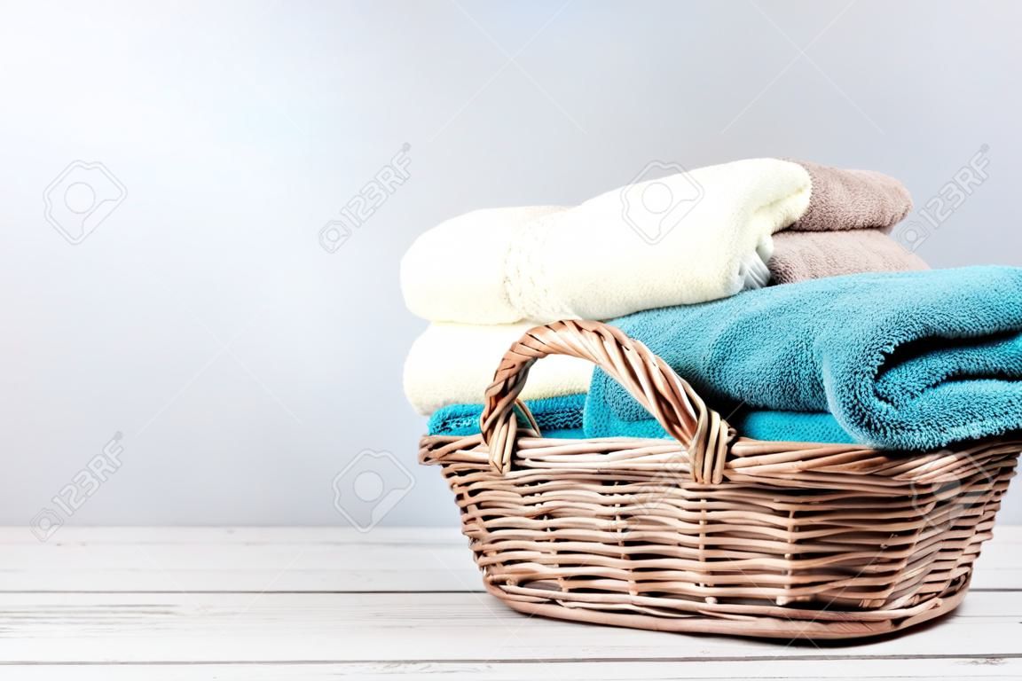 Toallas de baño de diferentes colores en la cesta de mimbre sobre fondo claro