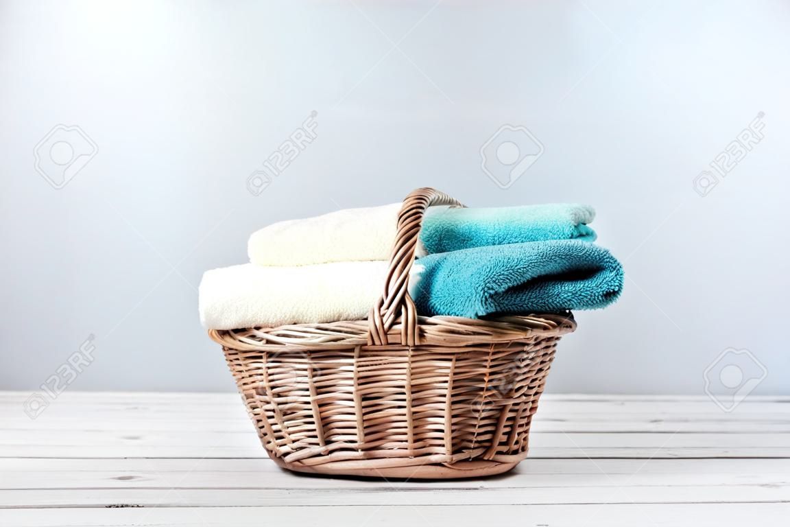 Badhanddoeken van verschillende kleuren in rieten mandje op lichte achtergrond