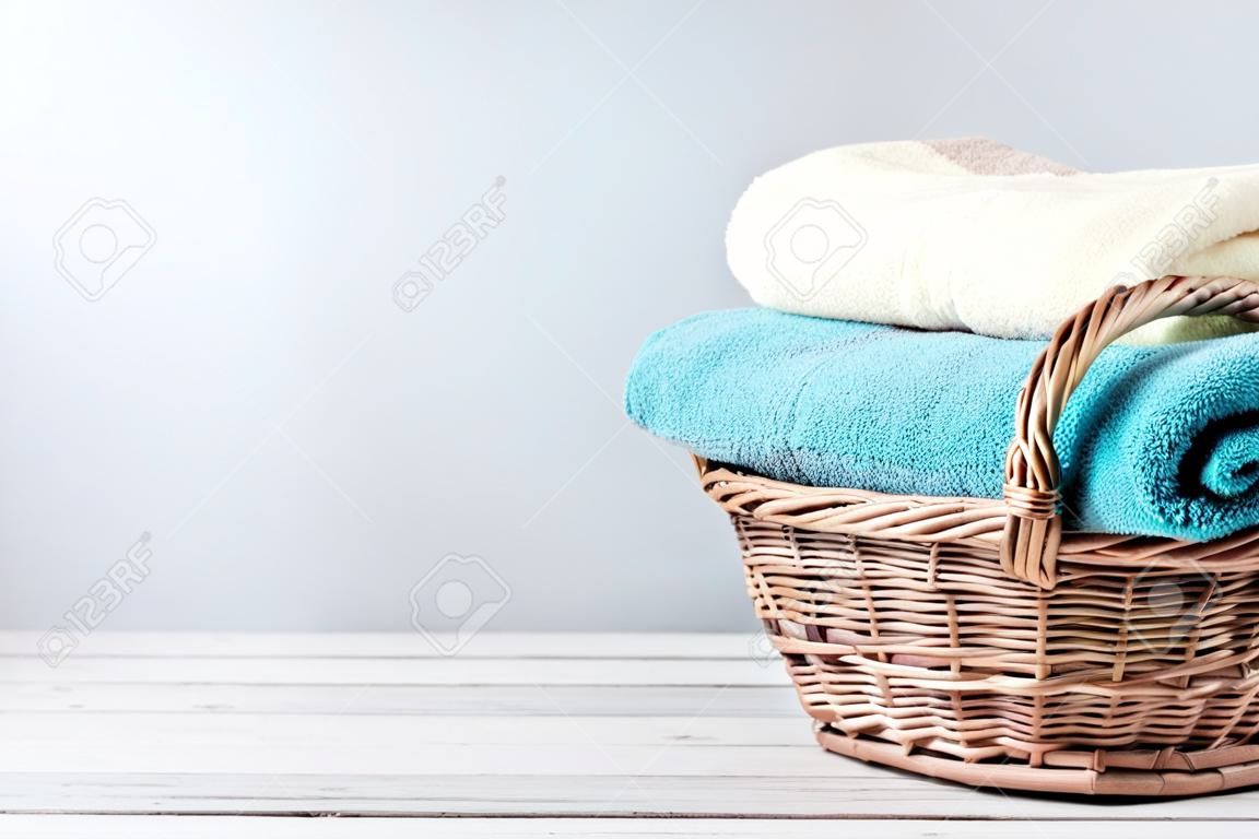 Badhanddoeken van verschillende kleuren in rieten mandje op lichte achtergrond
