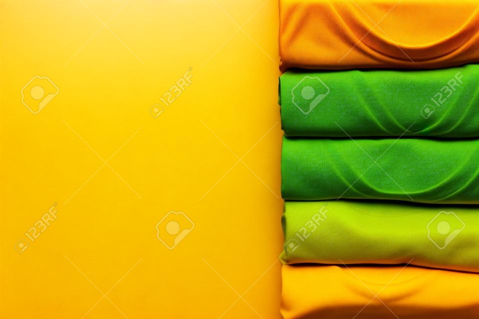 close up of rolled colorful clothes on yellow background