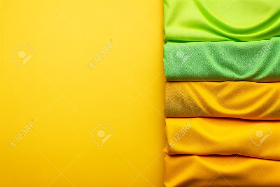 primo piano di vestiti colorati arrotolati su sfondo giallo