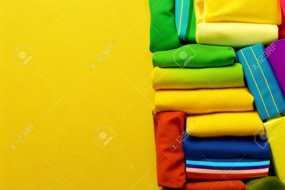 Gros plan de vêtements de t-shirt colorés roulés sur fond de table jaune, concept de voyage