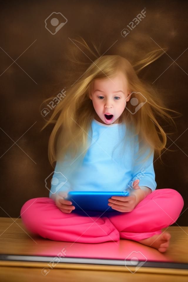 Chica sorprendida mirando una tabla mágica. Niño con Tablet PC