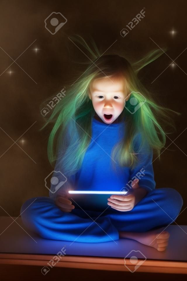 Sorpreso ragazza guardando una tavoletta magica. Bambino con il computer tablet