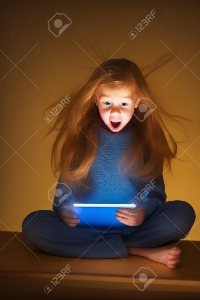 Sorpreso ragazza guardando una tavoletta magica. Bambino con il computer tablet