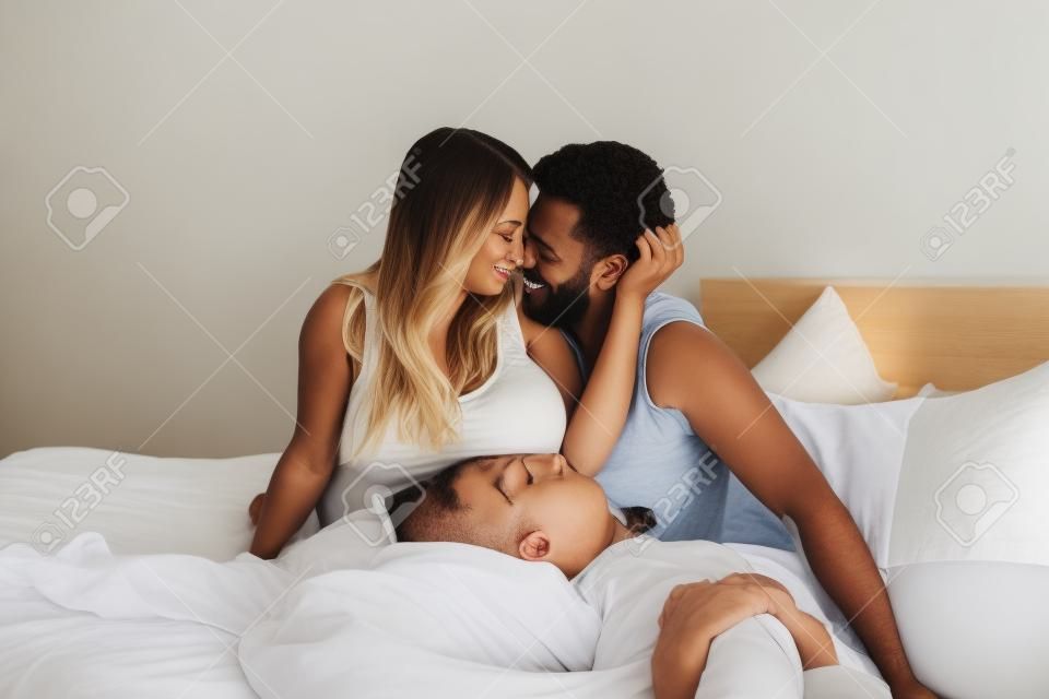 Schwangere Frau und Mann auf einem Bett im Schlafzimmer liegend