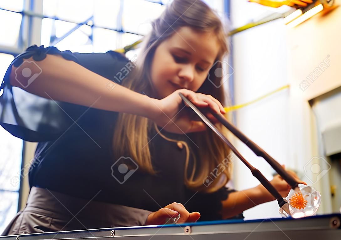 A glassblower student tries to make a flower out of glass
