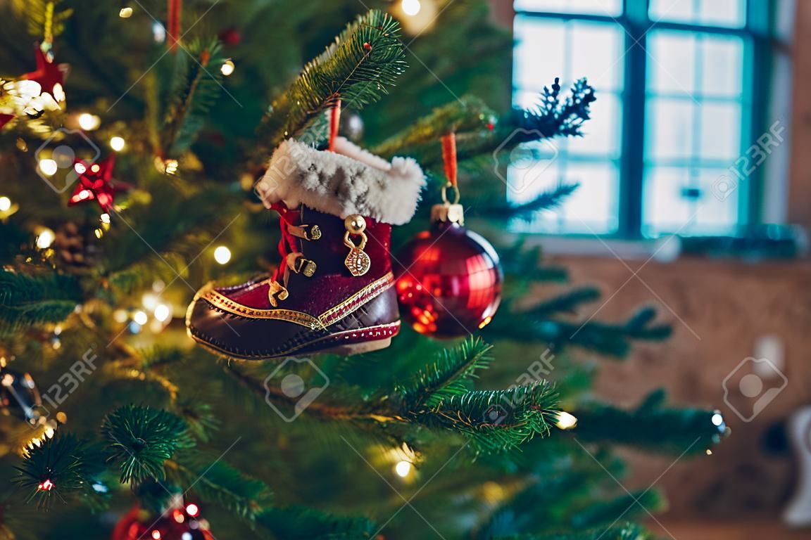 Close-up of Christmas tree branches with decorations, small decorative shoes