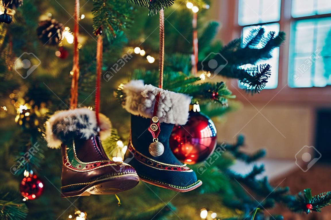 Close-up of Christmas tree branches with decorations, small decorative shoes