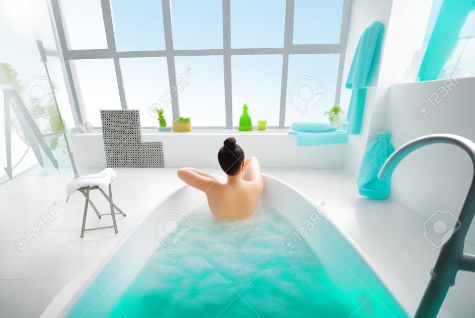 Relaxed lady taking bath, enjoying and relaxing while lying in bathtub, back view
