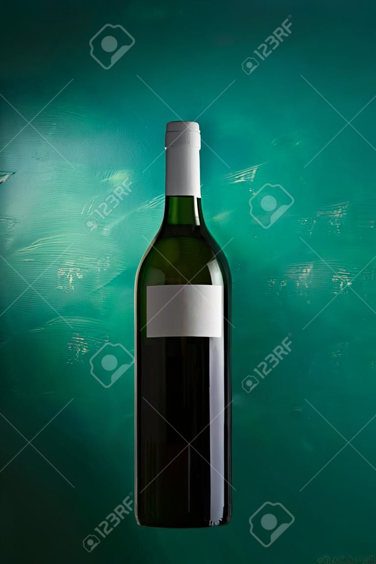 Botella de vino blanco sobre un fondo verde