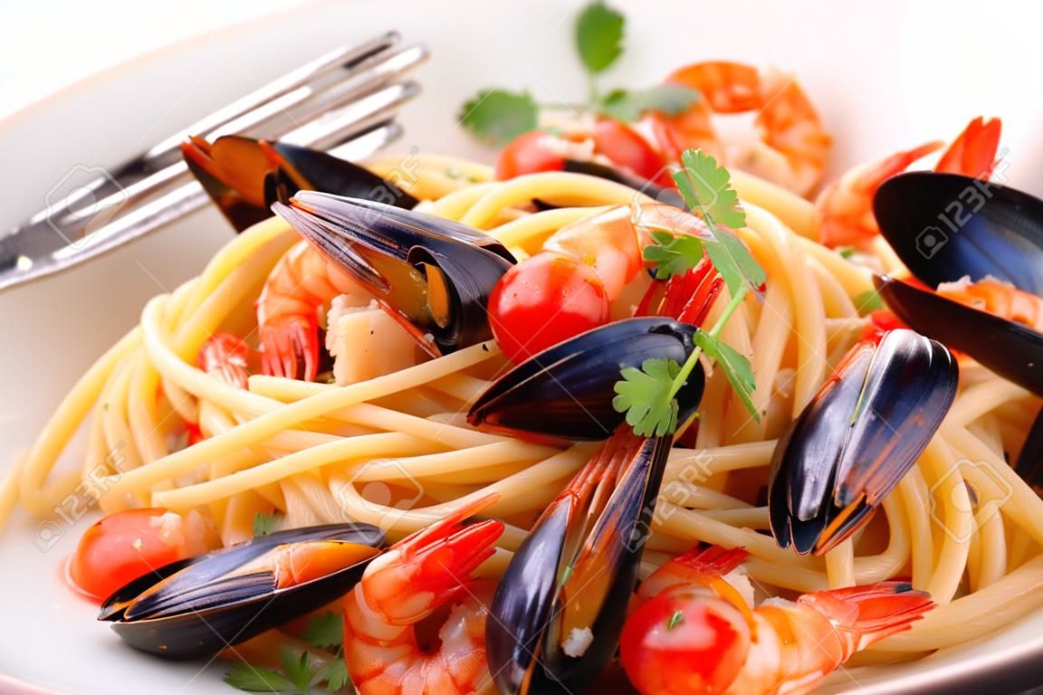 The pasta with seafood. Spaghetti with mussels and tiger prawns, traditional pasta with prawns close-up on a white background