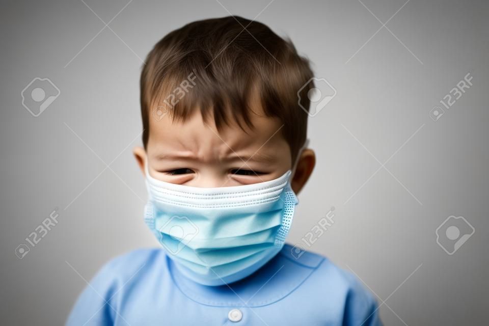 Crying toddler boy with medical mask on the face. Covid 2019 coronavirus outbreak. Sad child isolated on white. Boy at home
