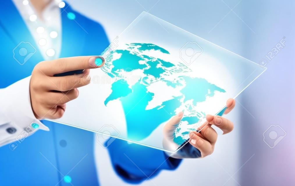 Modern global and international business technology concept. Businesswoman using futuristic transparent tablet with world map on screen. Export, foreign trade and communication concept.