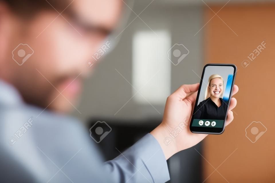Video call with mobile phone. Man and woman talking in online cam chat and virtual meeting conference on internet. Smiling face of a friend or girlfriend in videocall screen. Distance relationship.
