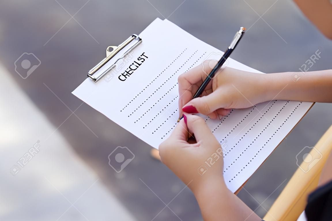 business female preparing checklist at office desk