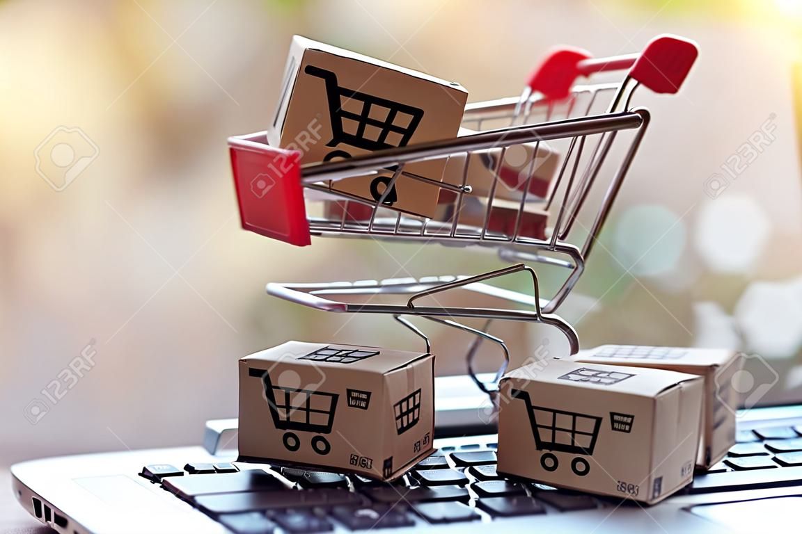 Koncepcja zakupów online - paczki lub kartony papierowe z logo koszyka na zakupy w wózku na klawiaturze laptopa. usługa zakupów w Internecie. oferuje dostawę do domu.