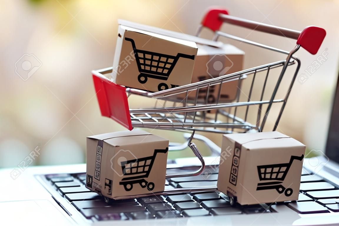 Online-Shopping-Konzept - Paket- oder Papierkartons mit einem Einkaufswagen-Logo in einem Trolley auf einer Laptop-Tastatur. Einkaufsservice im Online-Web. bietet Lieferung nach Hause an.