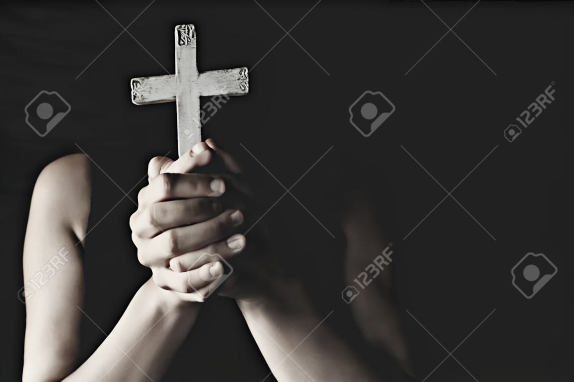 Gros plan des mains chrétiennes tenant la croix en priant.