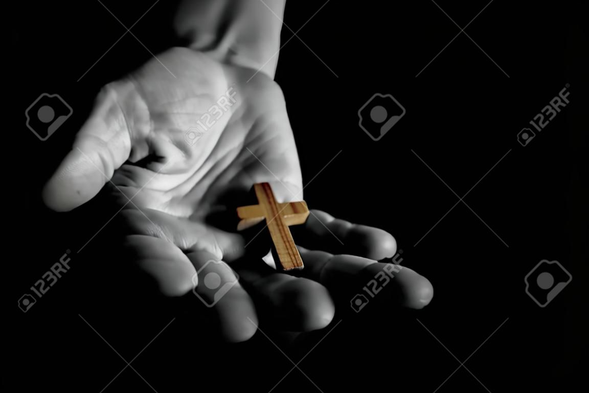 Uomo che dà segno di croce di legno semplice. Concetto di evangelizzazione Gesù Cristo agli altri. Low Key in bianco e nero con effetti di colore.
