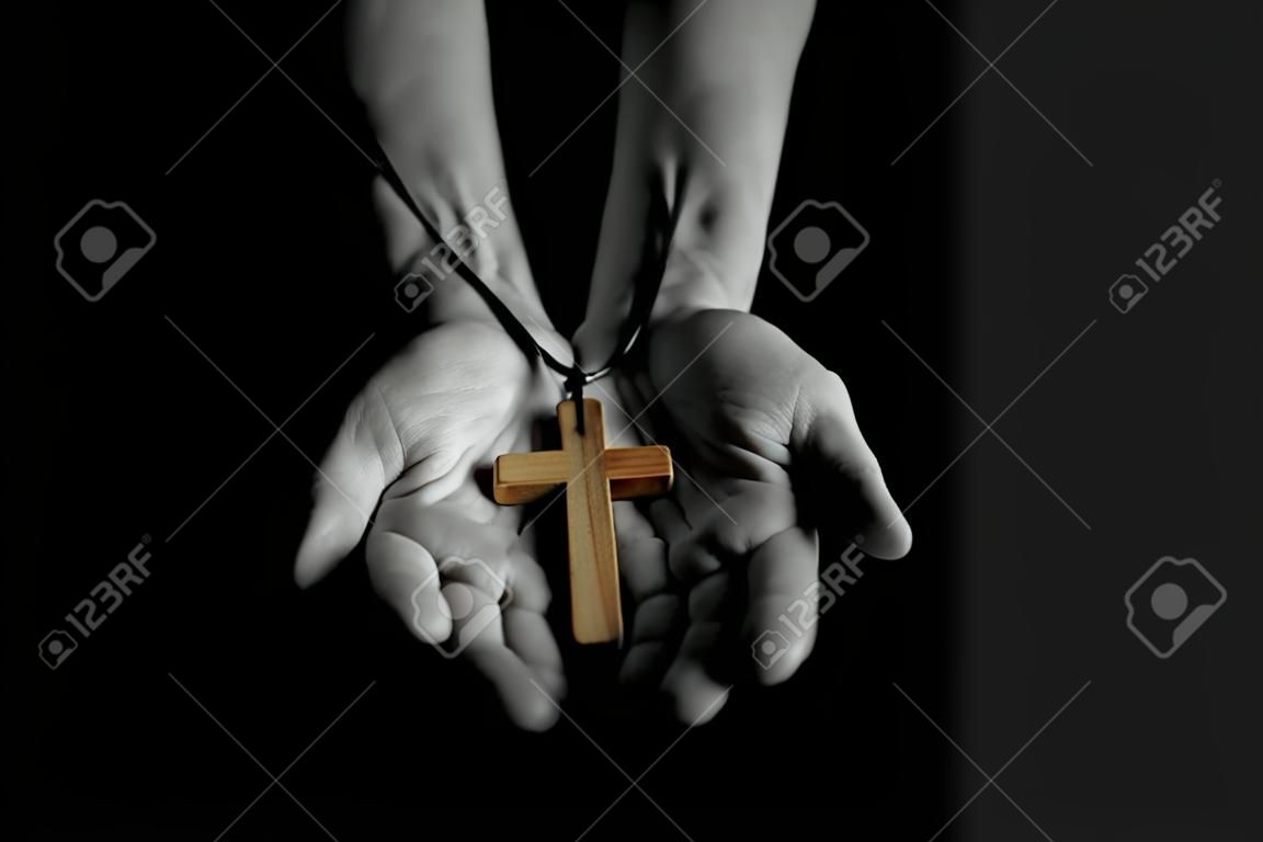 Uomo che dà segno di croce di legno semplice. Concetto di evangelizzazione Gesù Cristo agli altri. Low Key in bianco e nero con effetti di colore.