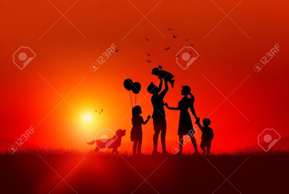 Szczęśliwy dzień rodziny, ojciec matka i dzieci sylwetka grając na trawie w zachód słońca.