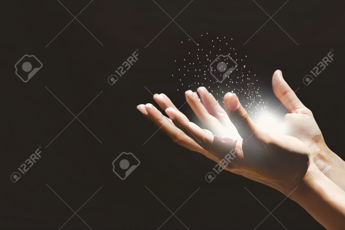 Männliche Hände beten mit Glauben an die Religion für Gottes Segen, wachsende Lichter und magisches Pulver, das auf den Händen schwimmt.