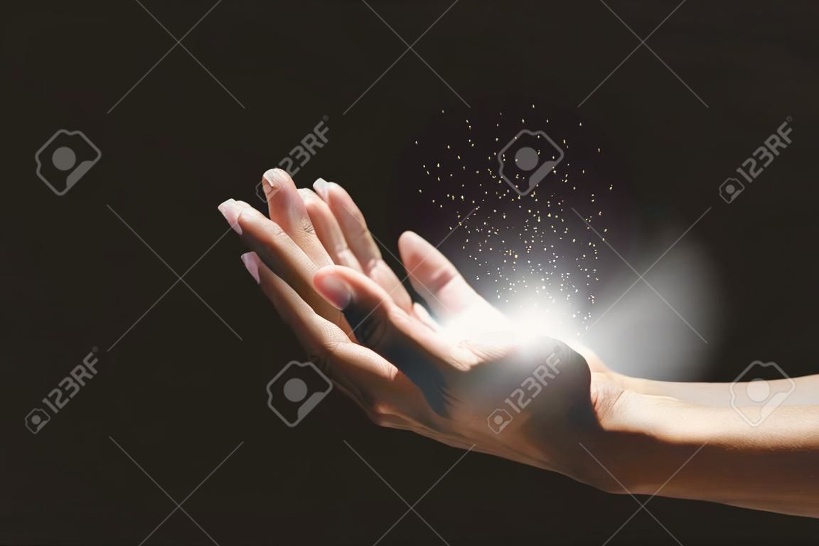 신의 축복을 위해 종교에 대한 믿음으로 기도하는 남성의 손, 손 위에 떠 있는 성장하는 빛, 마법의 가루.