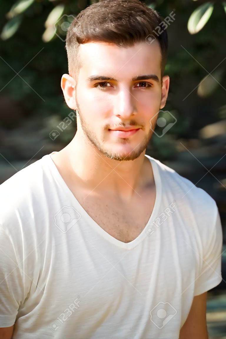 Portret van aantrekkelijke jongeman met wit t-shirt, kijken in camera