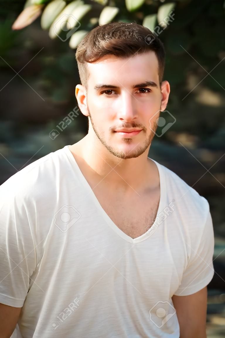 Portret van aantrekkelijke jongeman met wit t-shirt, kijken in camera