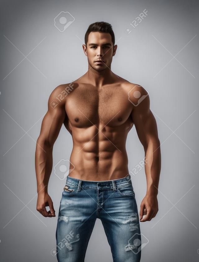 上半身裸筋肉の若い男のジーンズ、リラックスしたポーズは、白で隔離される前頭ショット