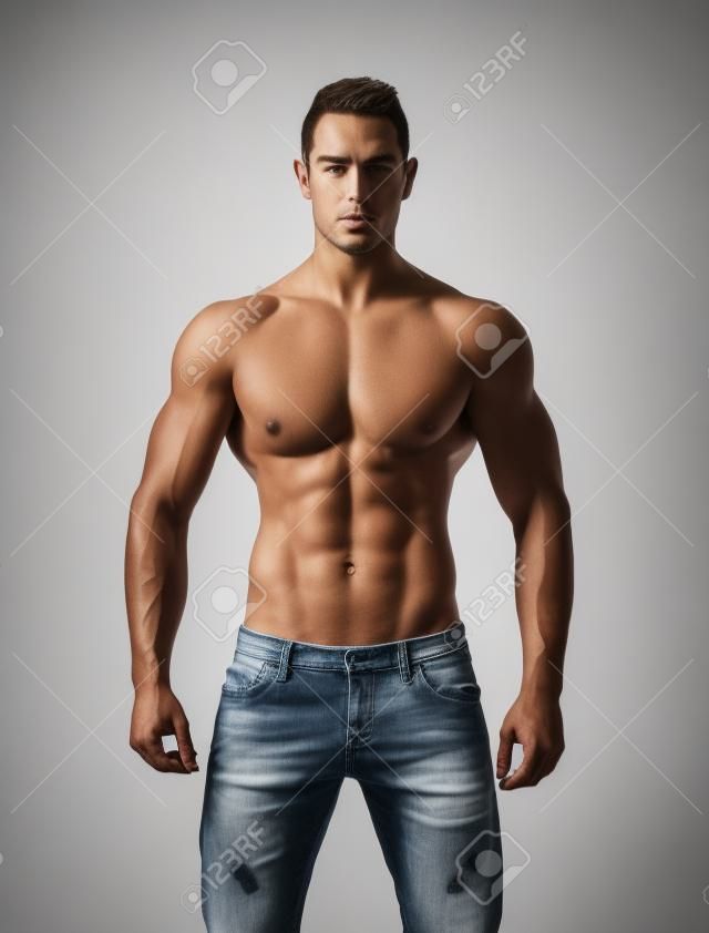 上半身裸筋肉の若い男のジーンズ、リラックスしたポーズは、白で隔離される前頭ショット
