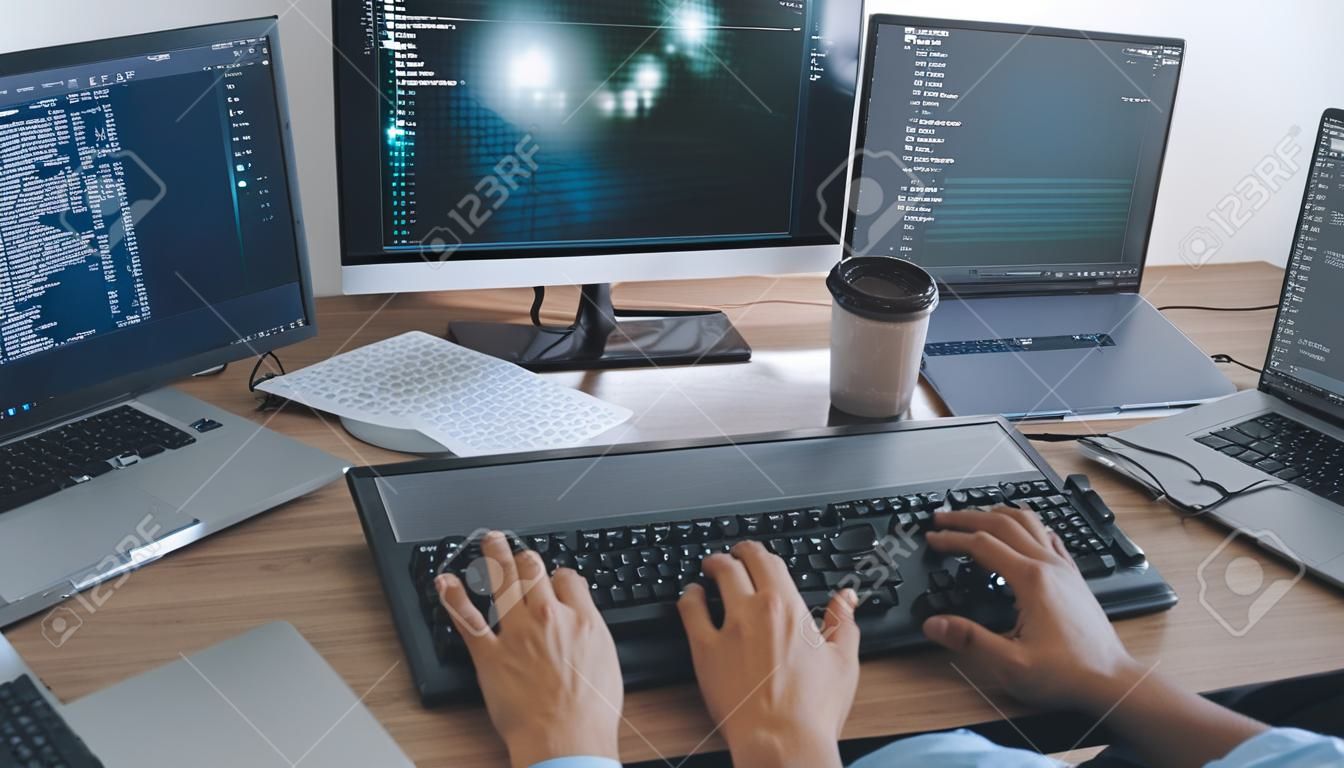 Programmatore che lavora sul computer in ufficio IT digitando la codifica dei dati nel software e controllando il codice sullo schermo del computer computer