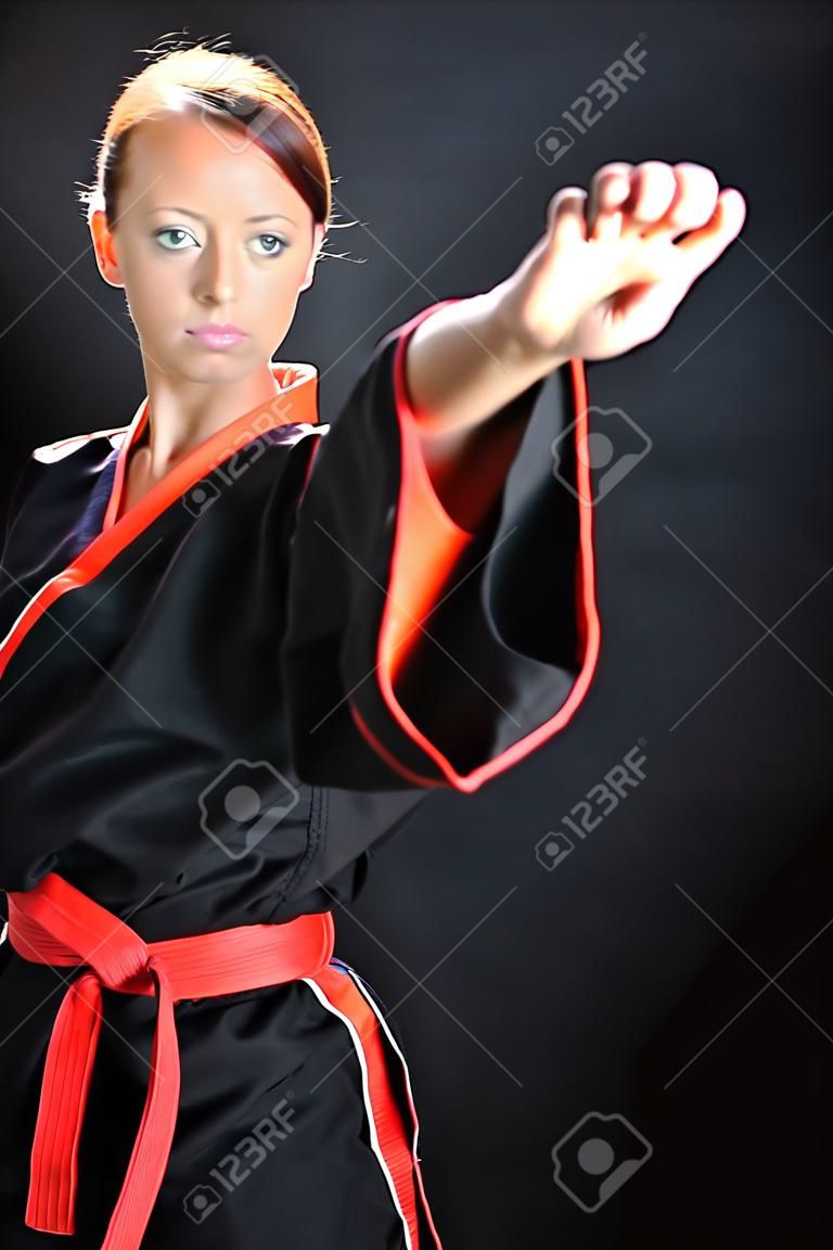 Karate girl posing in kimono against a black background