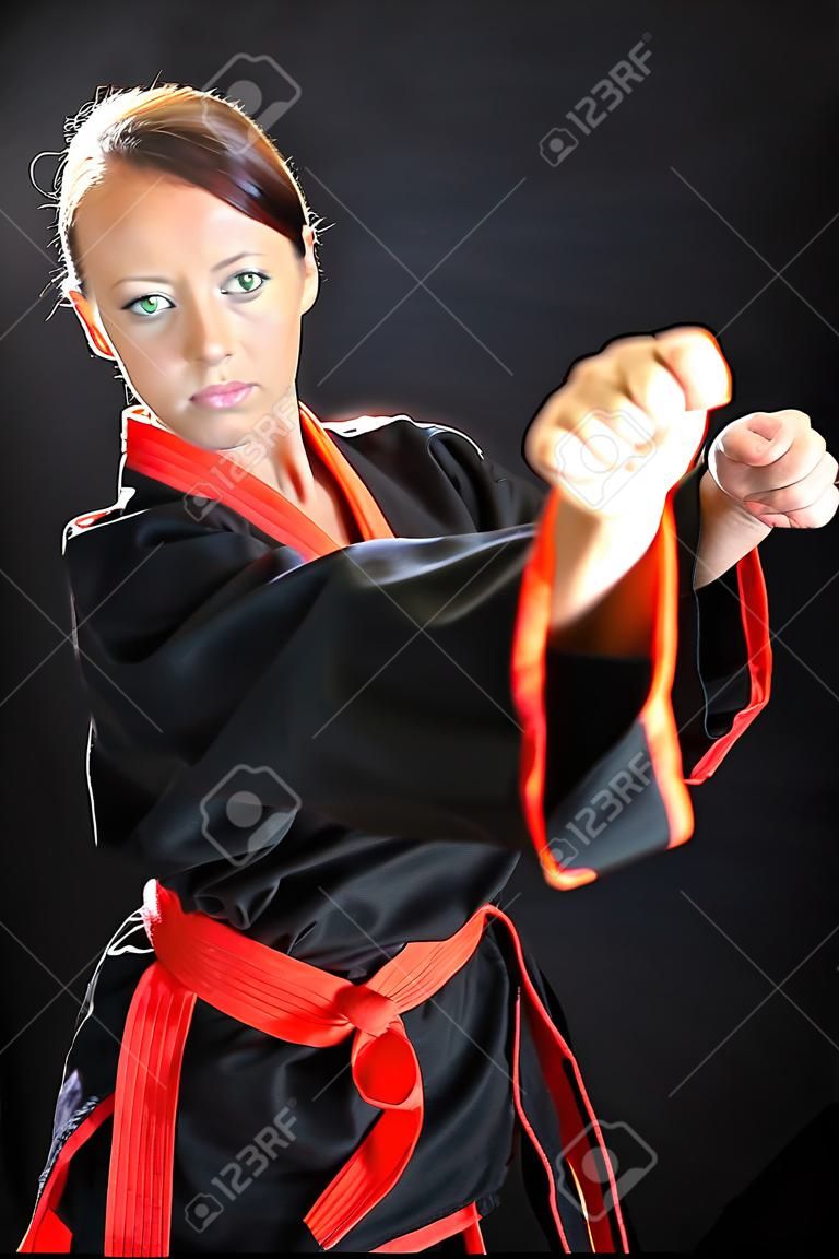 Karate girl posing in kimono against a black background